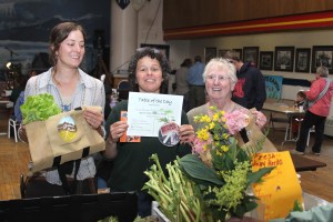 TableOfTheDayHopeMerrittEllenFrankensteinJudyJohnstone Hope Merritt, left, and Judy Johnstone, right, of Gimbal Botanicals and Sprucecot Gardens receive the Table of the Day Award from Ellen Frankenstein during the third Sitka Farmers Market of the season on Aug. 15.