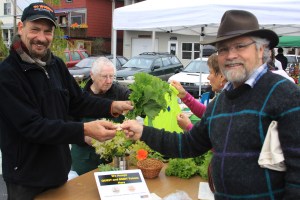 Kerry MacLane uses a token to purchase produce from Sitka Farmers Market vendor Keith Nyitray during the Aug. 3, 2013, Sitka Farmers Market.