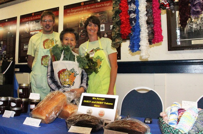 Sitka Farmers Market Assistant Manager Francis Wegman-Lawless, left, and Sitka Local Foods Network Board Member Brandie Cheatham, right, present the Table Of The Day Award to Phyllis Moore at the fourth Sitka Farmers Market of the 2015 summer on Saturday, Aug. 15, at the Alaska Native Brotherhood Founders Hall in Sitka. Moore sells jams and jellies, baked goods, and a variety of knitted items from hats and potholders to Afghan blankets. She received a gift bag with fresh greens and fresh rhubarb. This is the eighth year of Sitka Farmers Markets, hosted by the Sitka Local Foods Network. The next market is from 10 a.m. to 1 p.m. on Saturday, Aug. 29, at the Alaska Native Brotherhood Founders Hall, 235 Katlian St. Don’t forget the Sitka Slug Races take place at 12:30 p.m. at the Aug. 29 Sitka Farmers Market. For more information about the Sitka Farmers Markets and Sitka Local Foods Network, go to http://www.sitkalocalfoodsnetwork.org/, check out our Facebook page at https://www.facebook.com/SitkaLocalFoodsNetwork, or follow us on Twitter at https://www.twitter.com/SitkaLocalFoods. (PHOTO COURTESY OF SITKA LOCAL FOODS NETWORK)